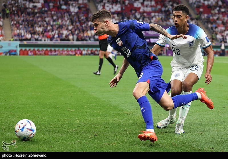 Christian Pulisic runs the ball getting marked by Jude Bellingham in the 2022 FIFA World Cup match England-USA