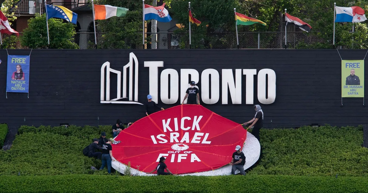 Activists place a banner covering the logo of the FIFA World Cup 2026 with the words "Kick Israel out of FIFA" in Toronto, Canada, June 12, 2026, on the day of the first game of the Canadian team in the World Cup against Bosnia-Herzegovina. (Photo by Jorge UZON / AFP)
