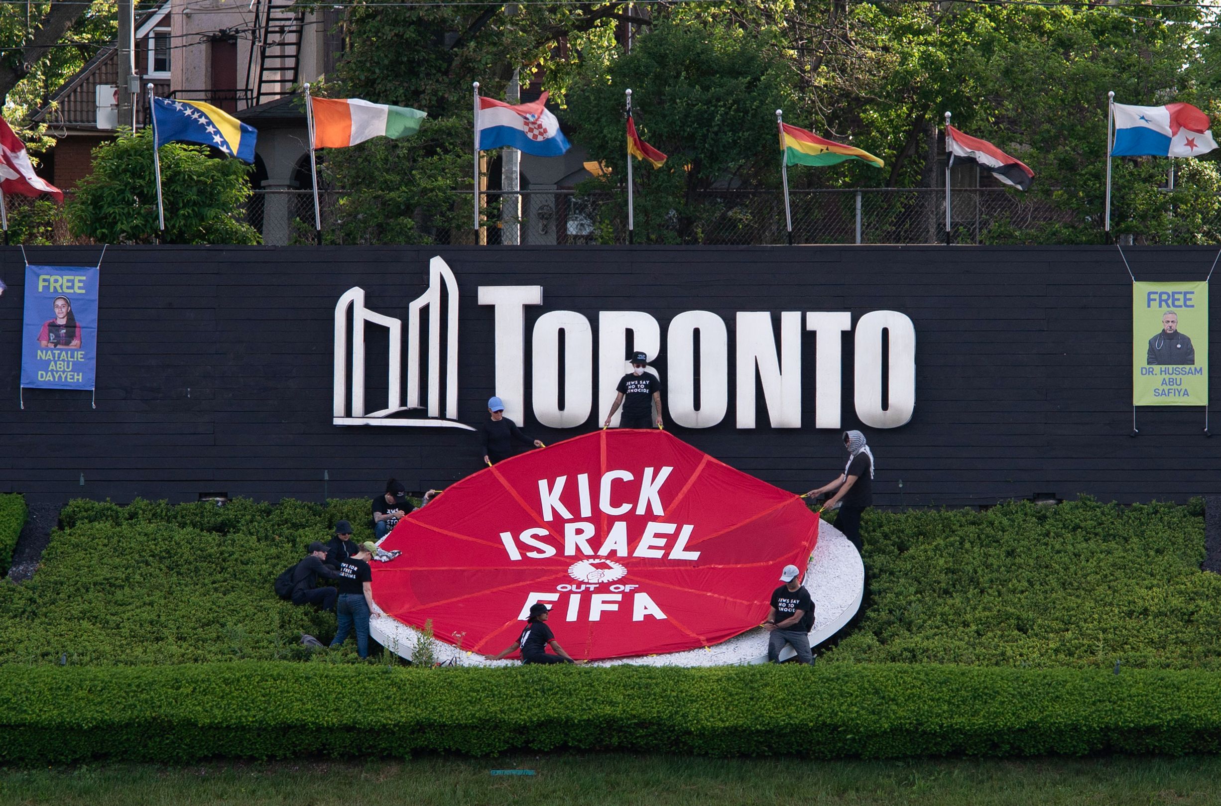 Activists place a banner covering the logo of the FIFA World Cup 2026 with the words "Kick Israel out of FIFA" in Toronto, Canada, June 12, 2026, on the day of the first game of the Canadian team in the World Cup against Bosnia-Herzegovina. (Photo by Jorge UZON / AFP)