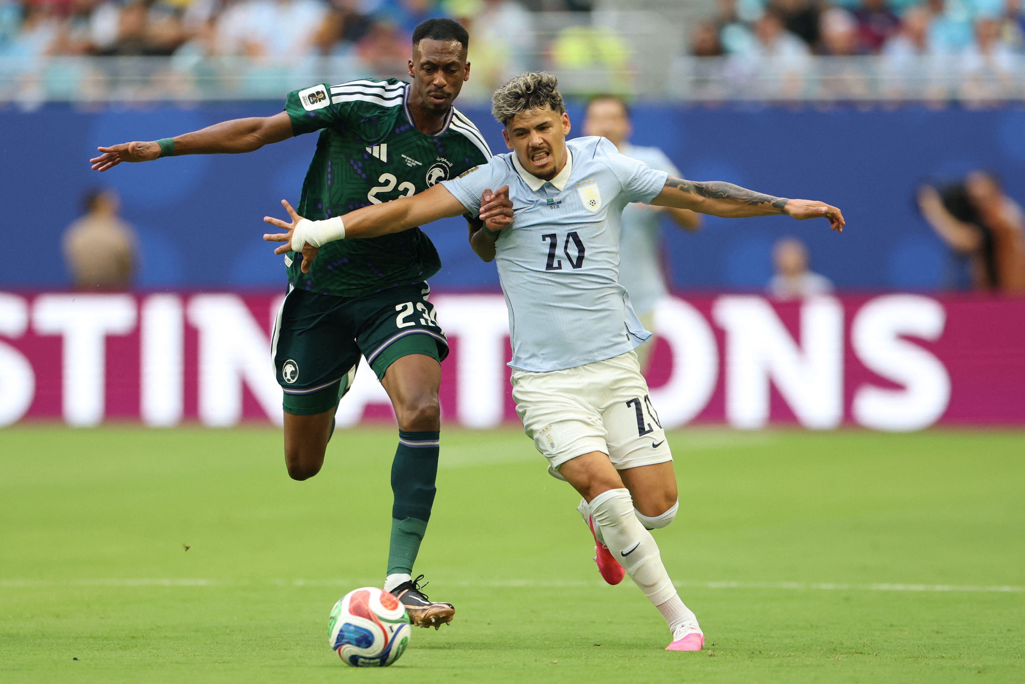 TOPSHOT - Saudi Arabia's midfielder #23 Mohamed Kanno and Uruguay's midfielder #20 Maximiliano Araujo fight for the ball during the 2026 World Cup Group H football match between Saudi Arabia and Uruguay at the Miami Stadium in Miami Gardens on June 15, 2026. (Photo by PATRICIA DE MELO MOREIRA / AFP)