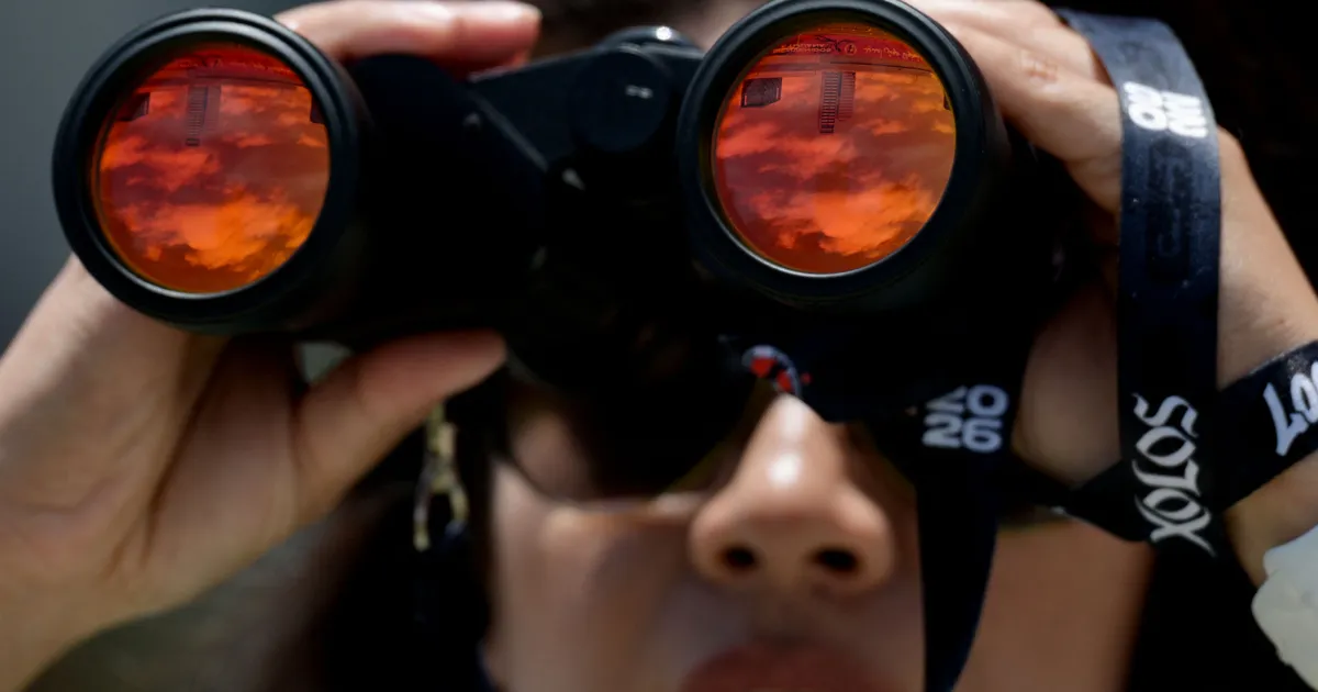 A security guard watches with her binoculars during a training session of Iranian players ahead of Iran's FIFA World Cup 2026 Group G football match against Belgium at Centro Xoloitzcuintle in Tijuana on June 18, 2026. (Photo by Guillermo Arias / AFP)