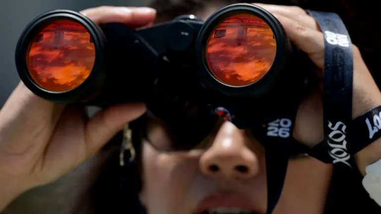 A security guard watches with her binoculars during a training session of Iranian players ahead of Iran's FIFA World Cup 2026 Group G football match against Belgium at Centro Xoloitzcuintle in Tijuana on June 18, 2026. (Photo by Guillermo Arias / AFP)