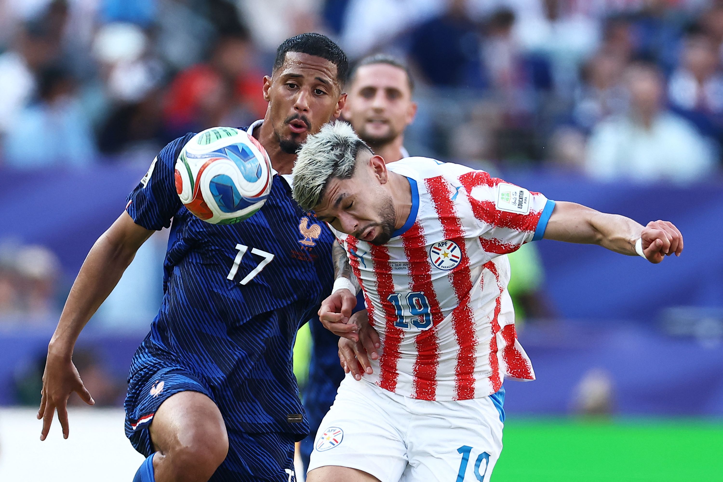 TOPSHOT - France's defender #17 William Saliba and Paraguay's midfielder #19 Julio Enciso fight for the ball during the 2026 World Cup round of 16 football match between Paraguay and France at the Philadelphia Stadium in Philadelphia on July 4, 2026.  (Photo by CHARLY TRIBALLEAU / AFP)