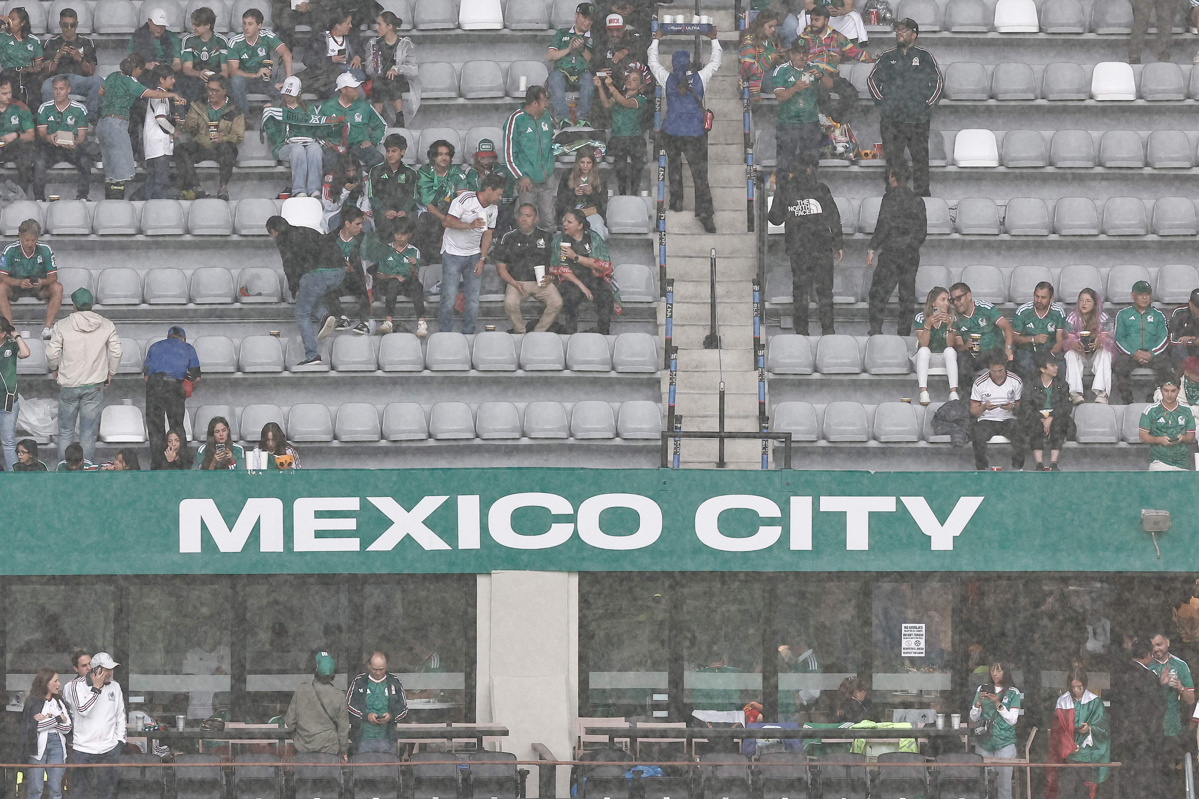 Mexican fans take shelter from the rain ahead of the 2026 World Cup round of 16 football match between Mexico and England at the Mexico City Stadium in Mexico City on July 5, 2026. (Photo by Ulises RUIZ / AFP)