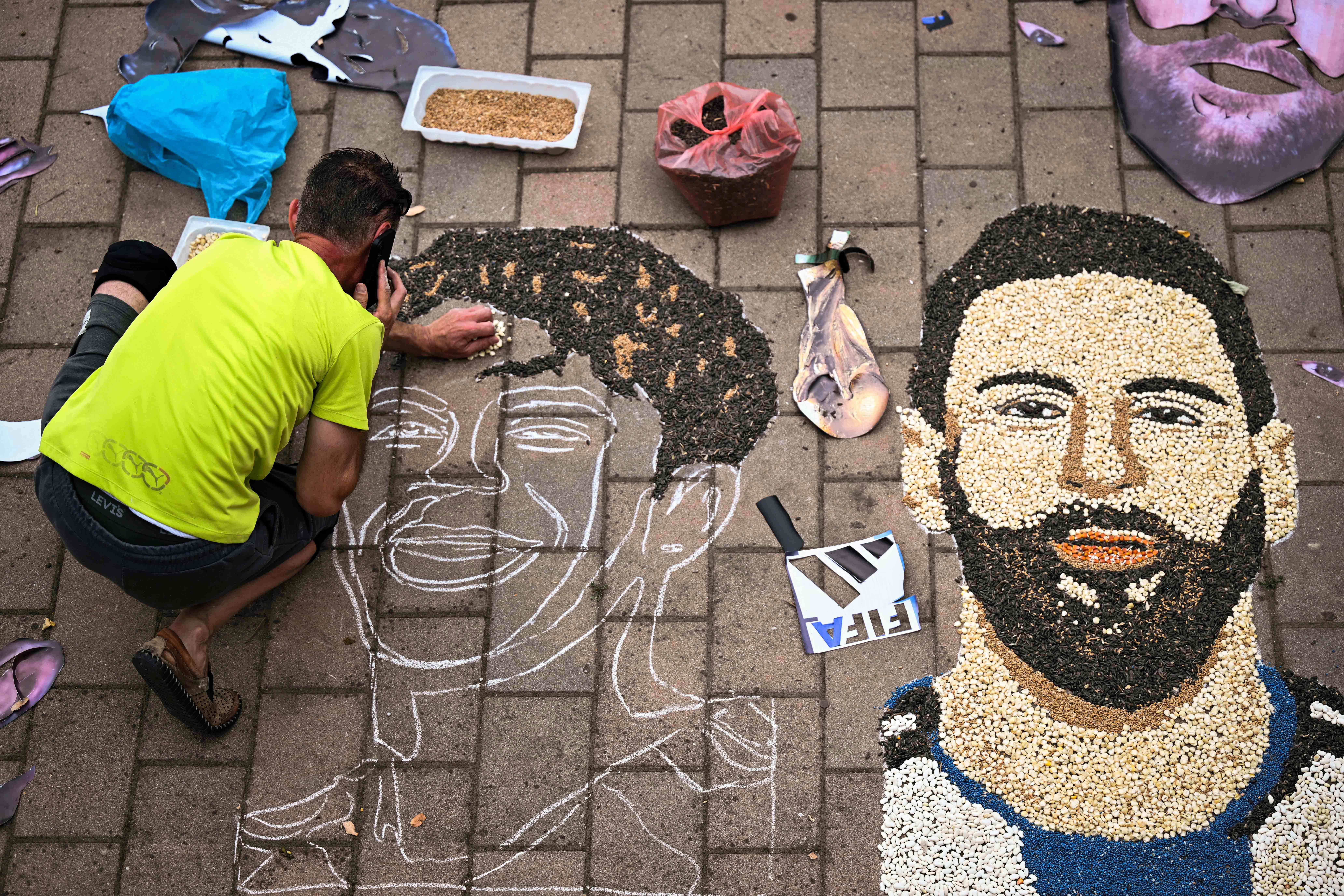 Kosovar artist Alkent Pozhegu works on a mosaic on the ground, made with grain and seeds, and depicting Argentina's forward #10 Lionel Messi (R) and Spain's forward #19 Lamine Yamal, in the town of Gjakova on July 16, 2026. Thousands of kilometres away from New York, where the Argentina and Spain football teams will compete for the World Cup title, in the western city of Gjakova, Alkent Pozhegu has made a mosaic depicting the two forward stars Lionel Messi and Lamine Yamal. (Photo by Armend NIMANI / AFP) / RESTRICTED TO EDITORIAL USE - MANDATORY MENTION OF THE ARTIST UPON PUBLICATION - TO ILLUSTRATE THE EVENT AS SPECIFIED IN THE CAPTION
