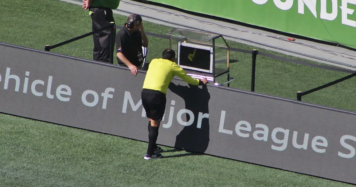 Referee Baldomero Toledo consults the video assistant referee during a Major League Soccer match between Seattle Sounders FC and Sporting Kansas City at CenturyLink Field . The review resulted in a red card for Sounders defender Chad Marshall .