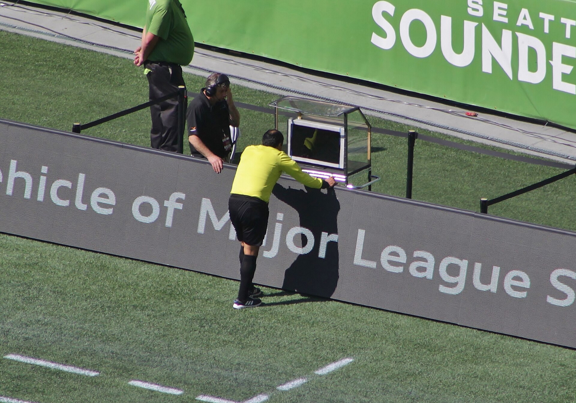 Referee Baldomero Toledo consults the video assistant referee during a Major League Soccer match between Seattle Sounders FC and Sporting Kansas City at CenturyLink Field . The review resulted in a red card for Sounders defender Chad Marshall .